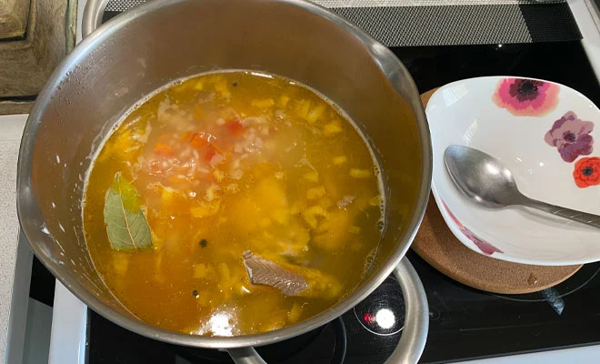 добавление обжаренных лука, моркови и перца, рыбы и специй для приготовления рыбного супа из горбуши